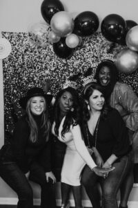 Photobooth guests celebrating New Year’s Eve with festive props and a balloon backdrop.